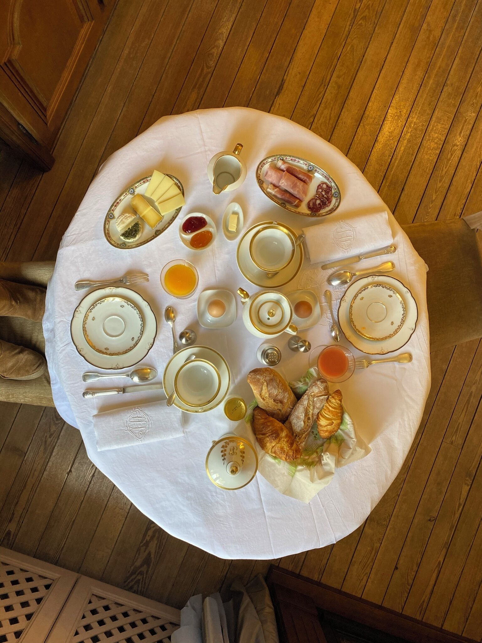 A breakfast setting with a variety of food items and tableware on a round table.