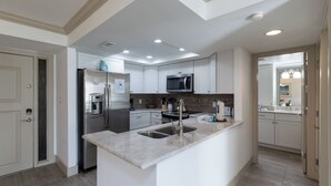 Una cocina moderna con armarios blancos, electrodomésticos de acero inoxidable y encimera de mármol.