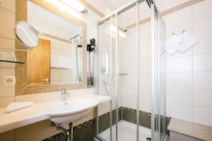 A modern bathroom with a glass shower enclosure, a sink with a mirror, and a towel rack.