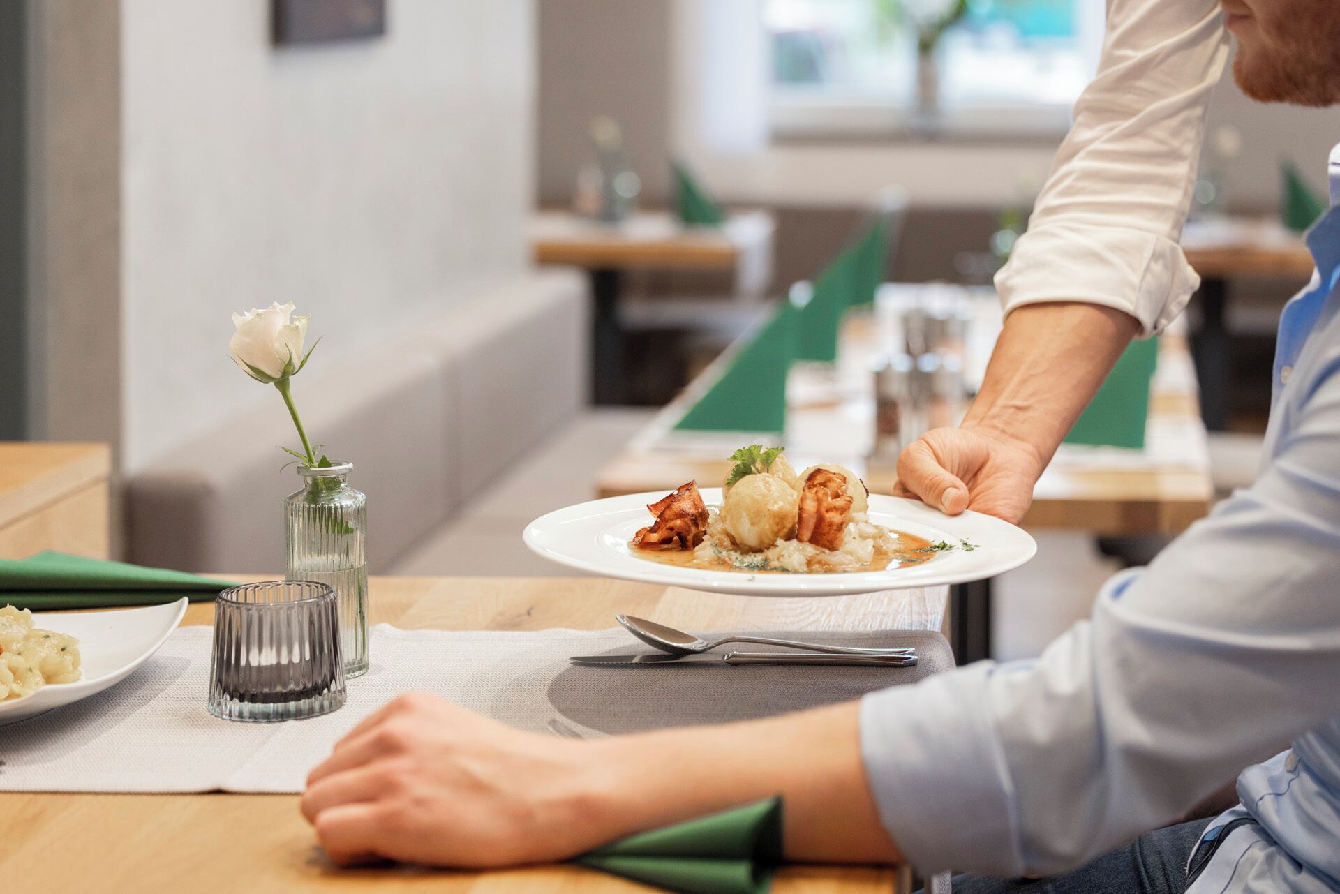 A person serving a plate of food at a restaurant.