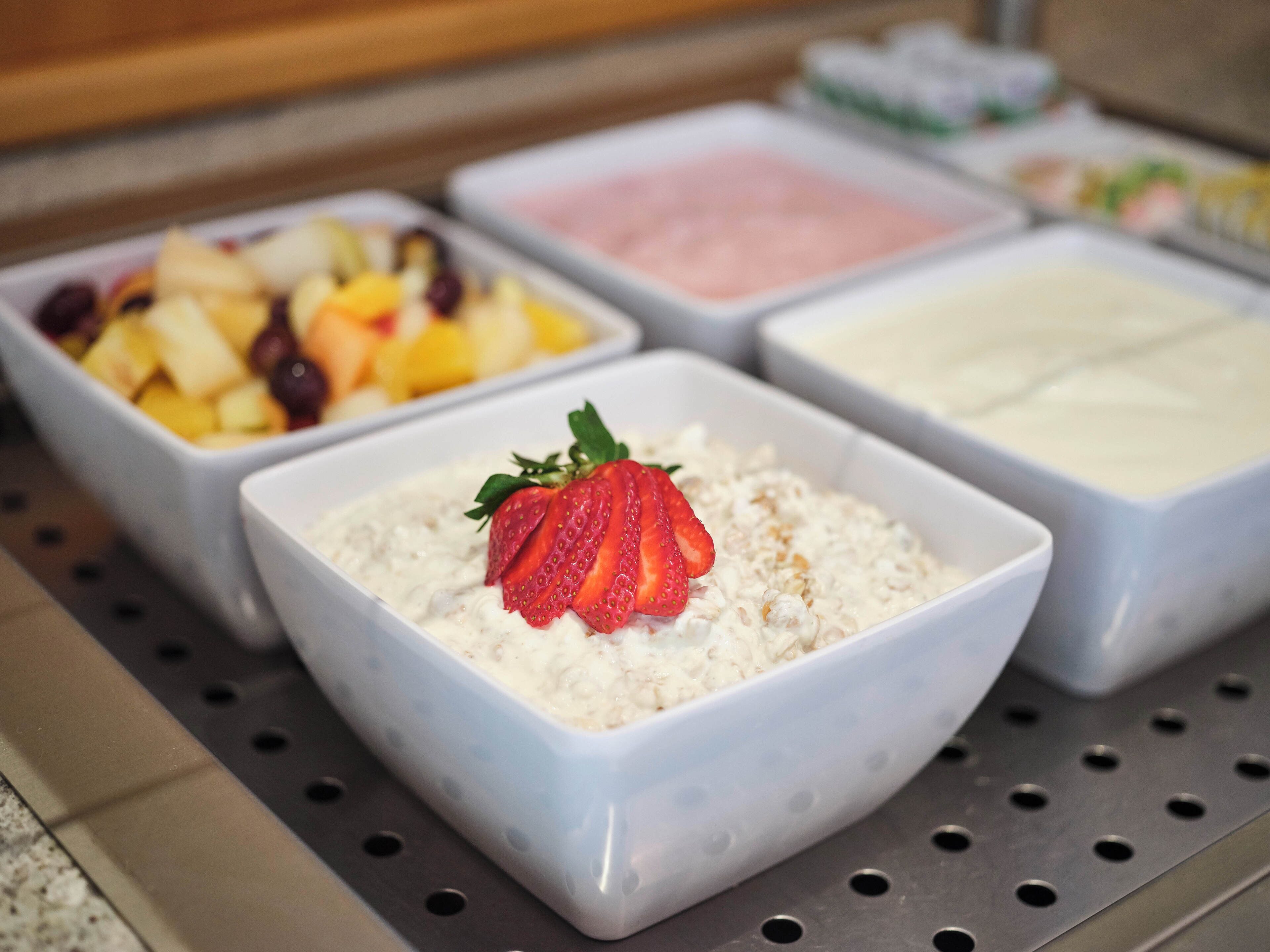 A breakfast buffet with various food options including cereal, fruits, and yogurt.