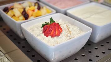 A breakfast buffet with various food options including cereal, fruits, and yogurt.