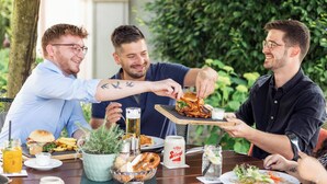 A group of people dining outdoors at a table with various foods, drinks, and a beer mug. - Hotel Jägerwirt (Lengau)