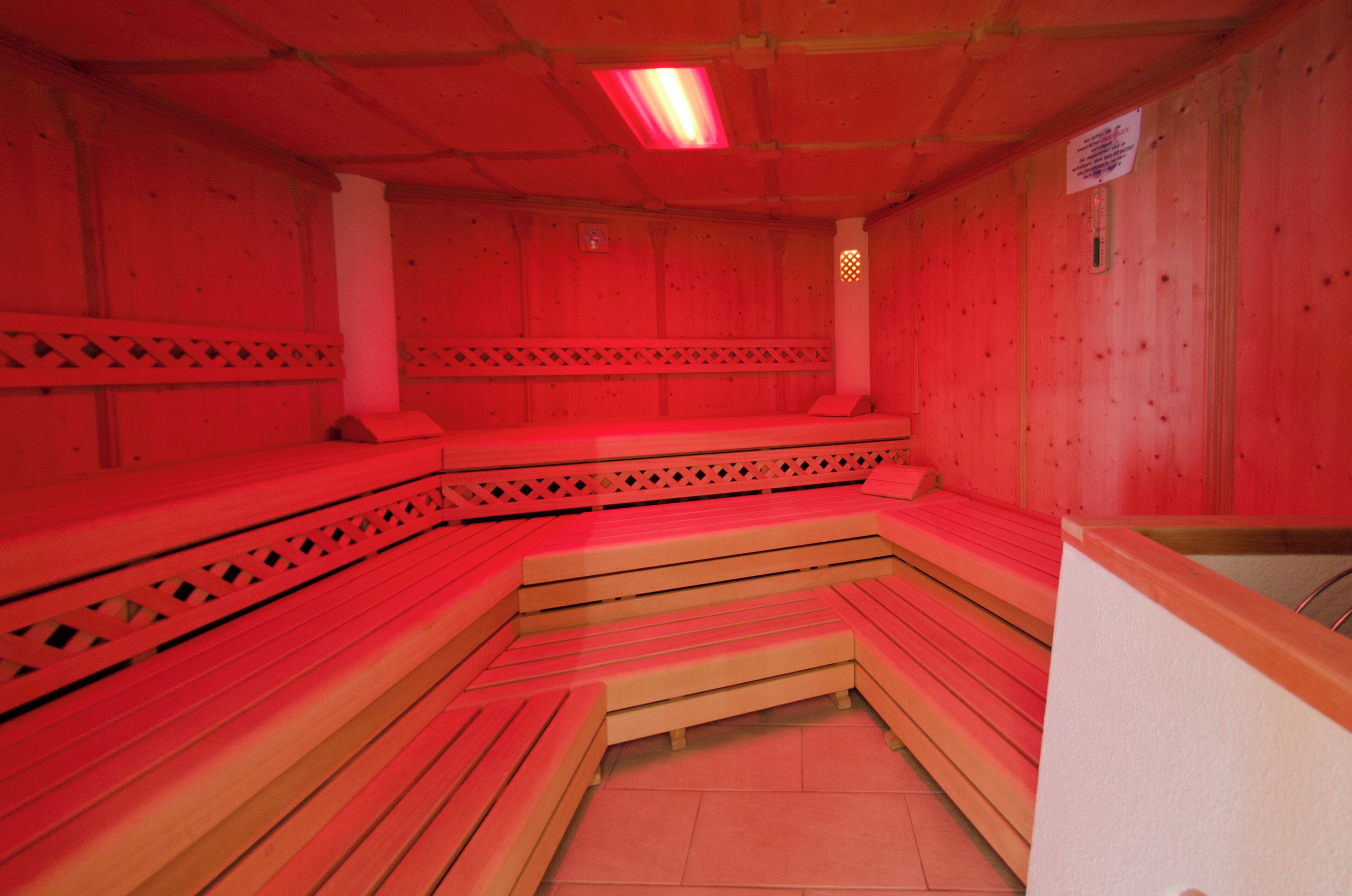 Eine Sauna mit Holzbänken und einer rot beleuchteten Decke.