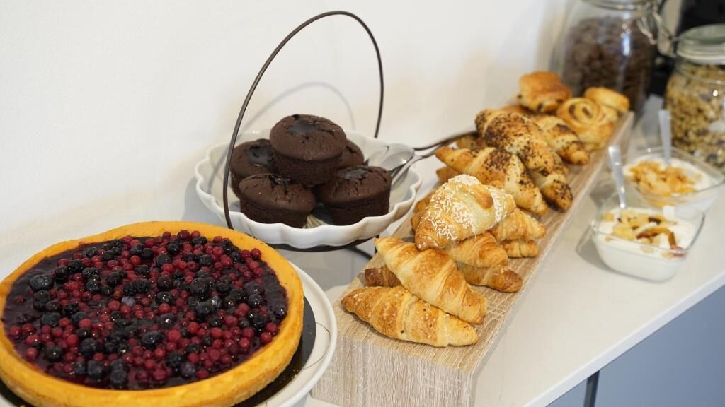 A breakfast buffet with various pastries, a berry tart, and a selection of muffins.
