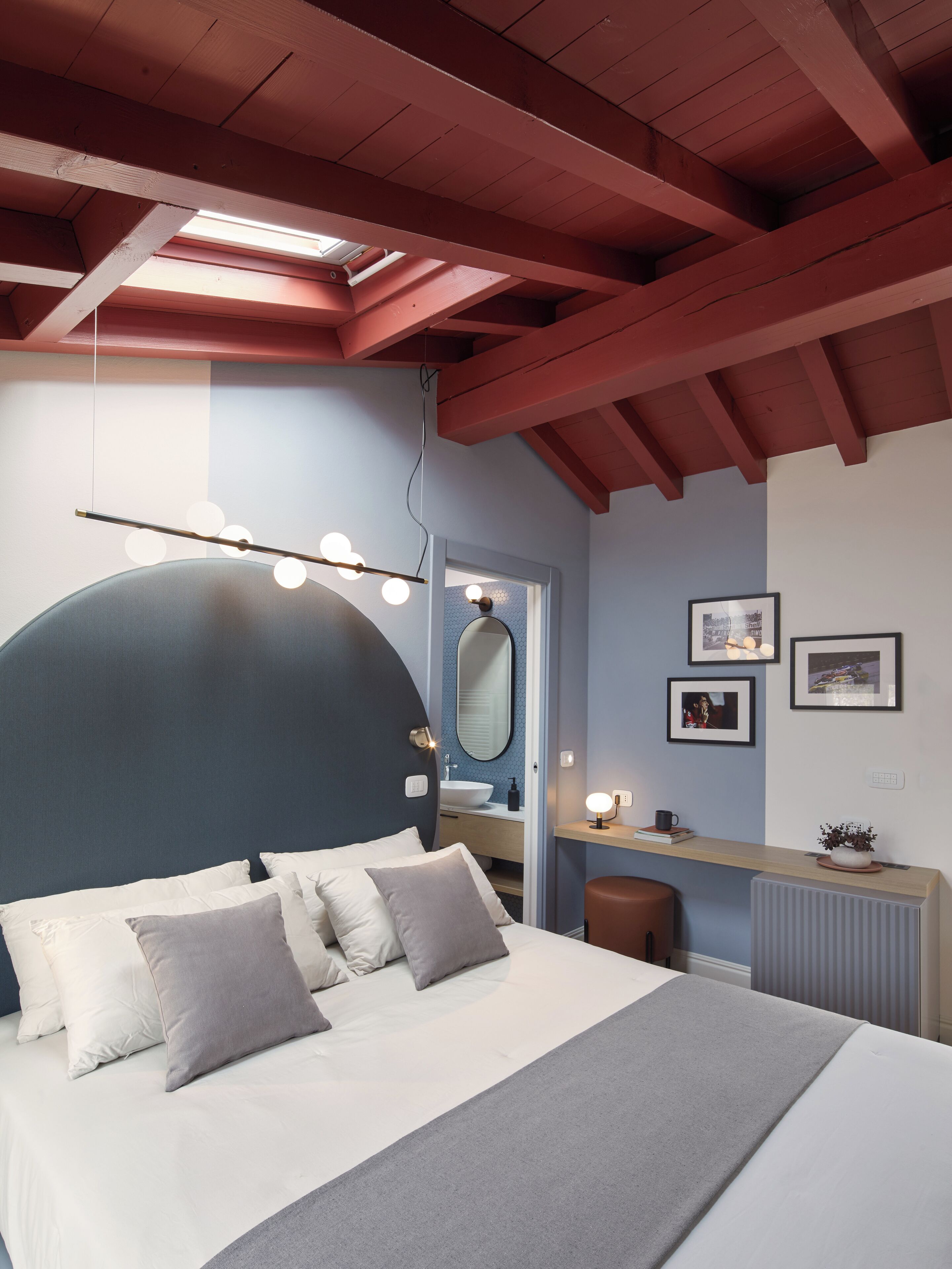 Een slaapkamer met een bed, nachtkastje, spiegel en ingelijste foto's aan de muur.