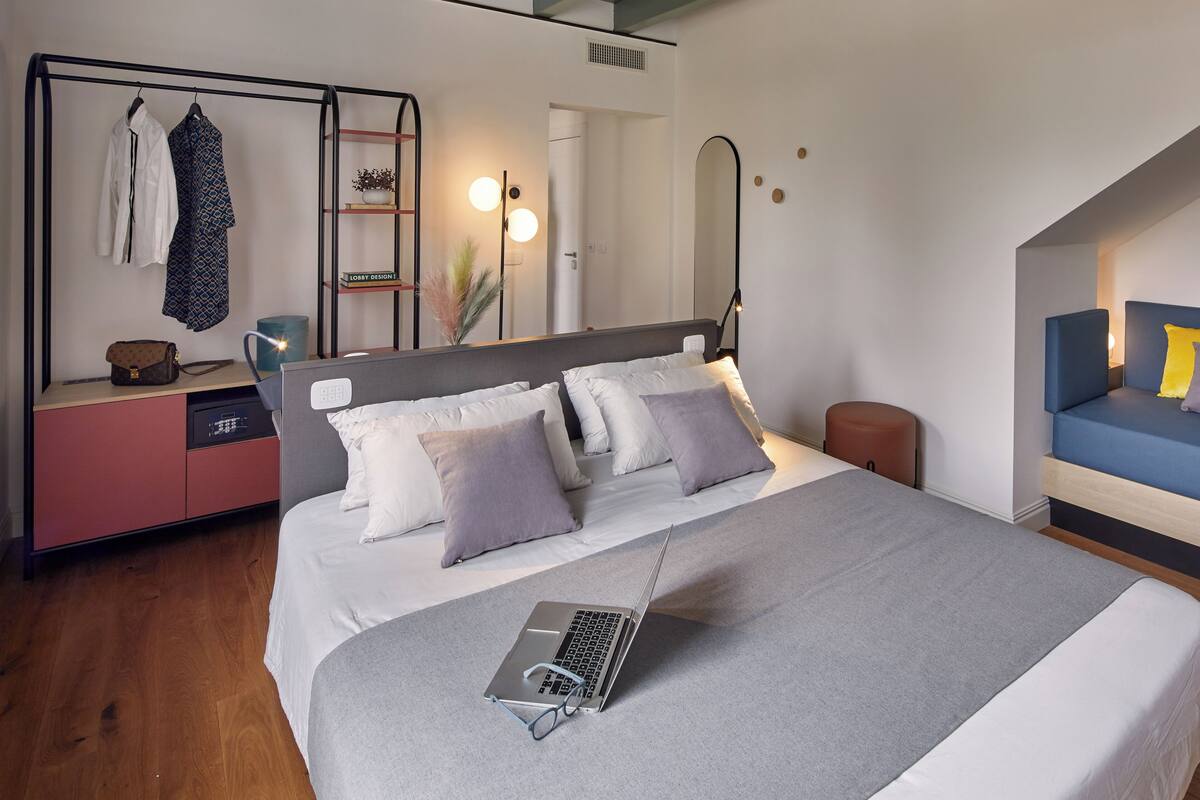 A modern bedroom with a bed, a desk, and a seating area.