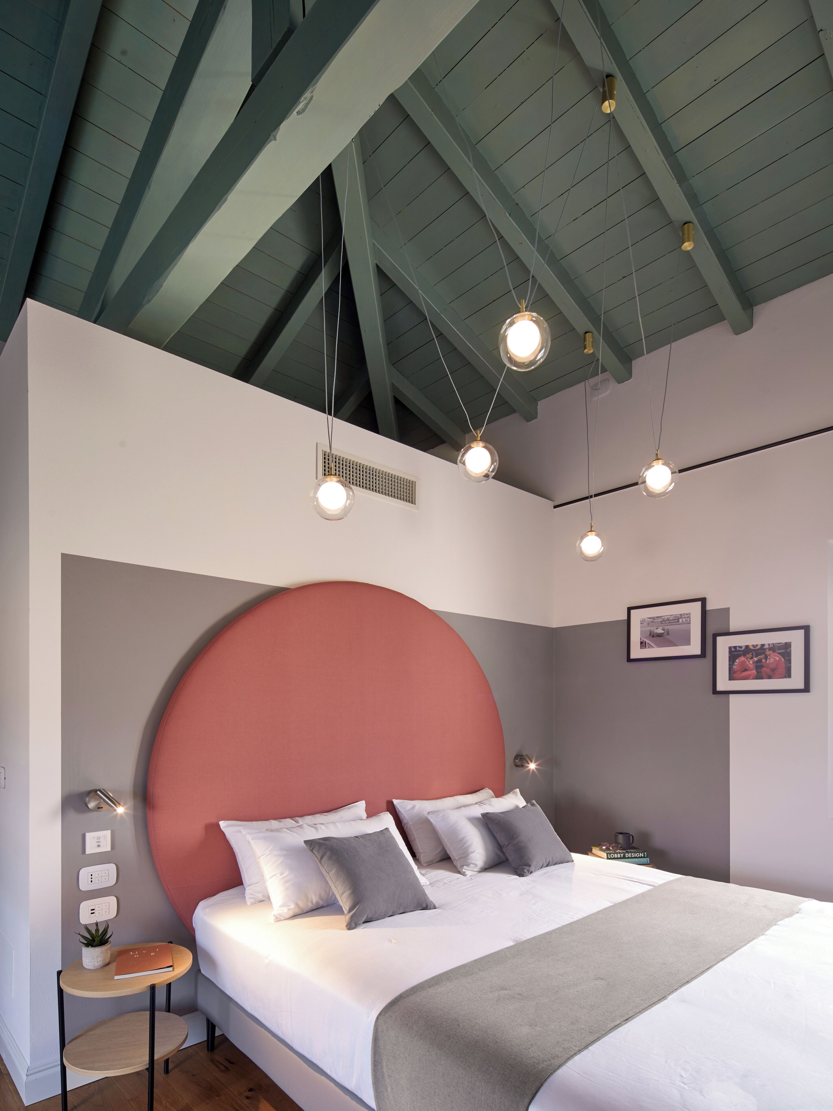 Un dormitorio moderno con una cama grande, un cabecero redondo e iluminación colgante.