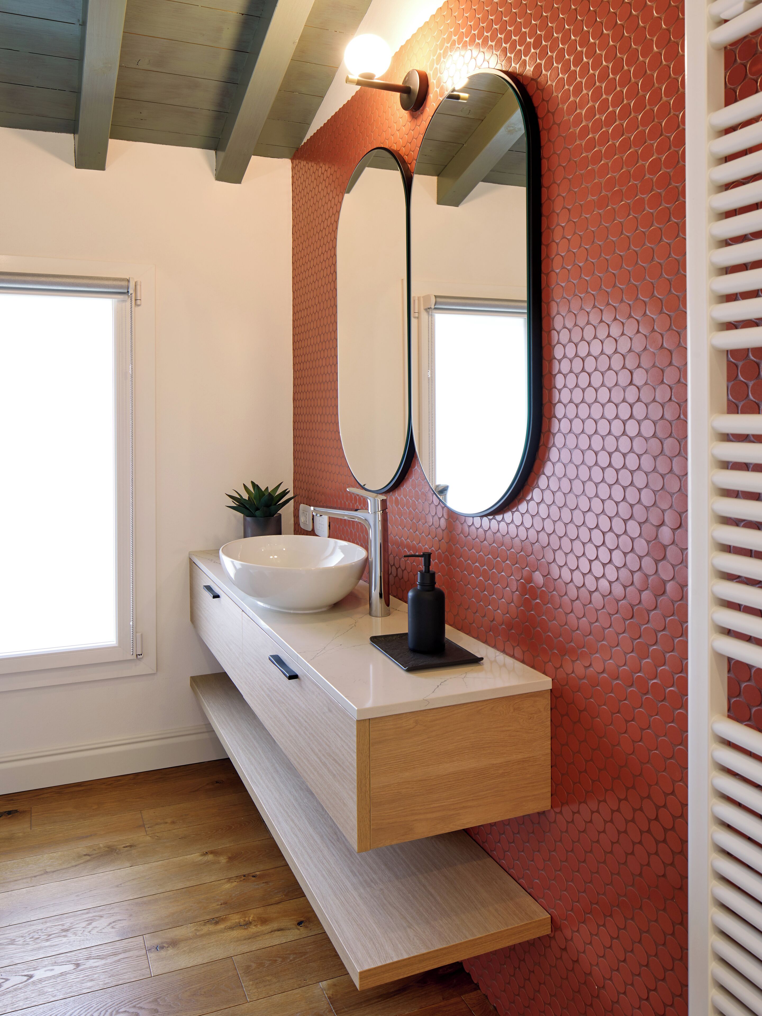 A bathroom with a white sink, a mirror, and a red patterned wall.