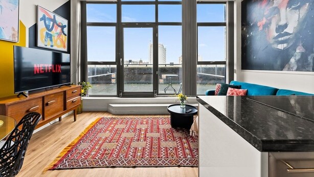 Ein modernes Wohnzimmer mit großem Fenster, Flachbildfernseher, Sofa und Couchtisch.