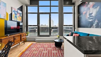 A modern living room with a large window, a flat-screen TV, a sofa, and a coffee table.