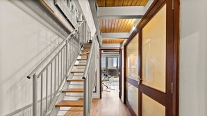 Ein modernes Interieur mit einer Holztreppe, einer Glastür und Blick in einen anderen Raum.