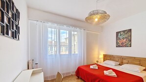 A hotel room with a bed, a chair, a desk, and a window with curtains. - N&J - TROPI AZUR - Terrace - Place du Pin  (Niza)