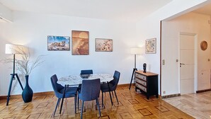 A dining area with a round table, chairs, and artwork on the walls. - N&J - TROPI AZUR - Terrace - Place du Pin  (Niza)