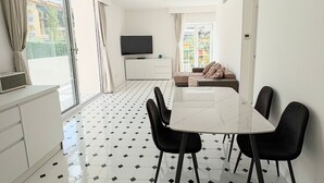 En moderne stue med spiseplads, store vinduer og et fladskærms-tv.
