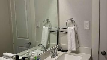 A bathroom with a large mirror, two sinks, and a towel rack.