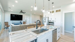 A modern kitchen with a marble countertop, stainless steel appliances, and pendant lighting. - Family Beach House (Fort Myers Beach)