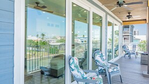 A covered outdoor area with glass doors, ceiling fans, and outdoor furniture. - Family Beach House (Fort Myers Beach)