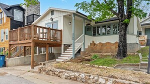 A residential property with a wooden deck, stone retaining wall, and a staircase leading to a covered porch. - The Raven's Roost Lake View Retreat 3bd 2ba (Rockaway Beach)