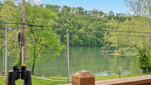 A wooden deck overlooking a lake with binoculars on the railing. - The Raven's Roost Lake View Retreat 3bd 2ba (Rockaway Beach)