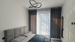 Un dormitori modern amb un llit gran, una taula de nit i una làmpada al sostre.