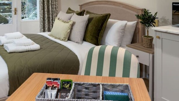 Un dormitorio con cama, mesita de noche y ventana con cortinas.