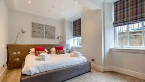 A neatly arranged bedroom with a large bed, a bedside table, and a lamp.