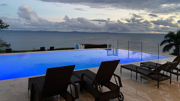 An infinity pool with lounge chairs, a view of the sea, and a cloudy sky. - Apartamento Vista Mare 9.102 (Samana)