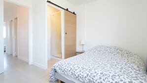 A bedroom with a bed, a sliding door, a small table with a lamp, and a shower area. - Hyères - Apartment T5 - Sea and salt water view - Refurbished (Hyères)