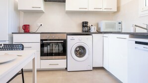 A compact kitchen with white cabinets, a microwave, a coffee maker, a red kettle, an oven, and a washing machine. - Hyères - Apartment T5 - Sea and salt water view - Refurbished (Hyères)