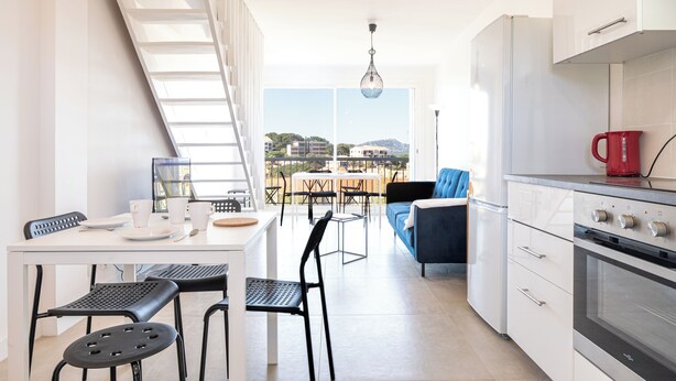 A modern kitchen with white cabinets, a red kettle, and a dining area with a table and chairs. - Hyères - Apartment T5 - Sea and salt water view - Refurbished (Hyères)