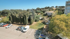 A parking lot with several cars, a white van, and a building with a balcony. - Hyères - Apartment T5 - Sea and salt water view - Refurbished (Hyères)