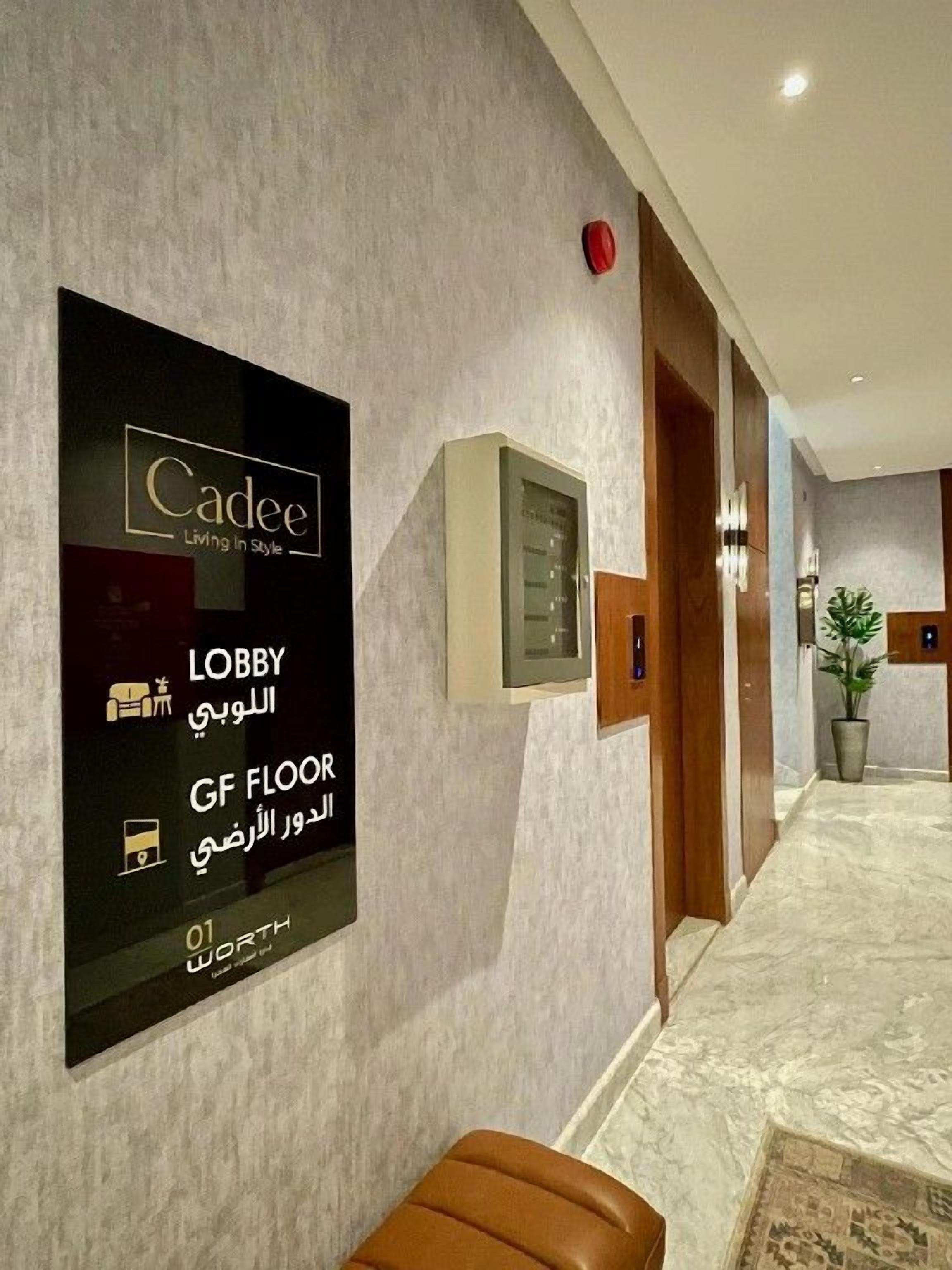 A hotel lobby with a sign indicating the lobby and GF floor, a reception desk, and a bench.