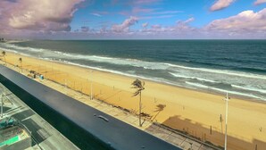 A beach with a road running parallel to it, and a cloudy sky above. - Comfortable Studio with Ocean View in Armação (Salvador)
