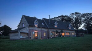 A two-story house with a sloped roof, large windows, and a well-maintained lawn. - Wilderness Reserve - Cartshed (Halesworth)