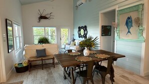 A dining area with a wooden table, chairs, and a bench. There are potted plants, a mirror, and wall art.