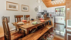 Een eetgedeelte met een houten tafel, stoelen en een keuken op de achtergrond.