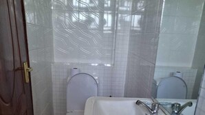 Kylpyhuone, jossa on wc, pesuallas ja peili.