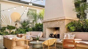 An outdoor patio with wicker furniture, a round coffee table, and a built-in fireplace. - Charleston Loft | Exclusive Party-Friendly Rental (Charleston)