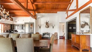 A spacious living area with a wooden ceiling, a dining table surrounded by chairs, and a kitchen in the background. - Charleston Loft | Exclusive Party-Friendly Rental (Charleston)
