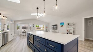 A spacious kitchen with a large island, white cabinetry, and pendant lighting. - Dockside Dreams - Summer Pool and Canal Retreat! (Palm Coast)