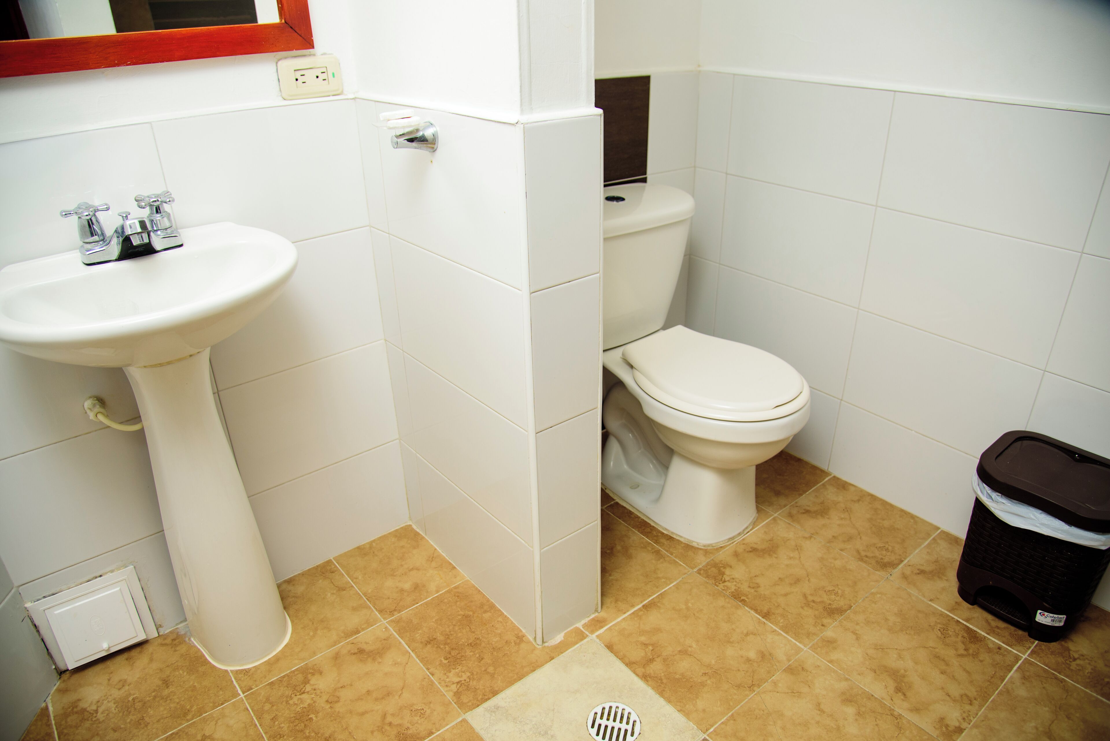 Un baño con lavamanos, inodoro y cubo de basura.