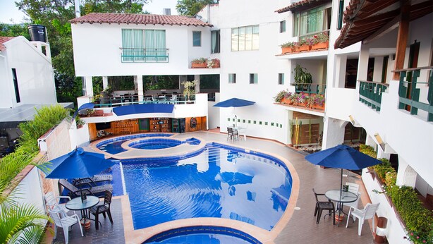 Una piscina con diseño circular, rodeada de mobiliario exterior y sombrillas.