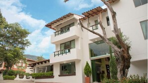Un edificio de varios pisos con fachada blanca, balcones y ventanas grandes.