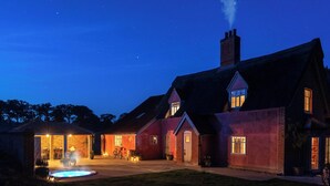 Une grande maison avec une piscine, un patio couvert et une allée bien éclairée la nuit.