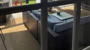 Un patio techado con mobiliario de mimbre, una silla colgante y vistas a un lago con barcos.
