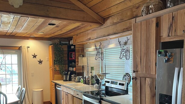 Una cocina con armarios de madera, un refrigerador de acero inoxidable, una estufa y un fregadero.