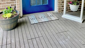 A blue door with a glass panel, a welcome mat, and a hanging sign with flowers. - Spacious 1-bedroom guesthouse in lovely Wiggins with WiFi, AC (Wiggins)