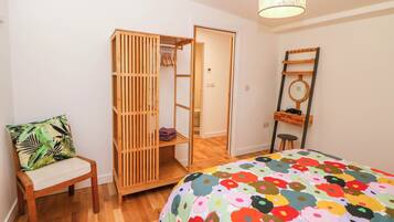 Ein Schlafzimmer mit einem Bett, einem Holzschrank, einem Stuhl und einem Schreibtisch mit Spiegel.