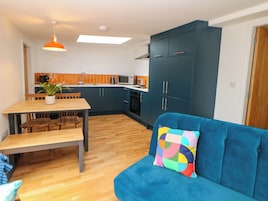 Un espacio habitable compacto con comedor, kitchenette y un sofá con un cojín colorido.